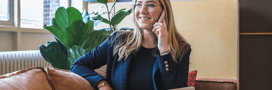 Woman sits on sofa with laptop on lap and makes phone call, which stands for the right to information for call notes