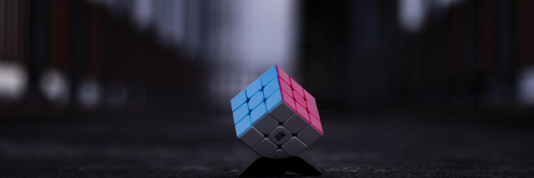 Zauberwürfel mit blauer, pinker und weißer Seite liegt auf einer dunklen Straße