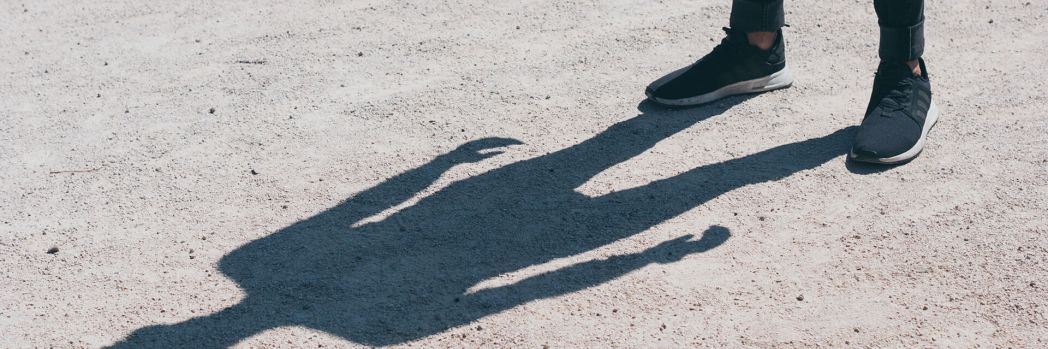 Man standing in the sun looking at his shadow, which stands for data protection of sensitive data.