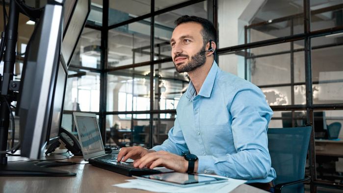 Mann sitzt an seinem Schreibtisch und arbeitet an digitalisierten Speditionsaufträgen im Order Management
