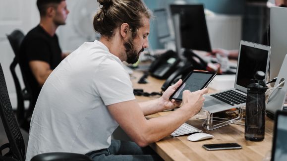Logistikdienstleister prüft Auftragsstatus einer Kundenbestellung an seinem Tablet.