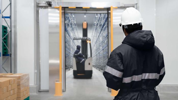 Intralogistiker fährt mit logistischer Hardware durch das Lager
