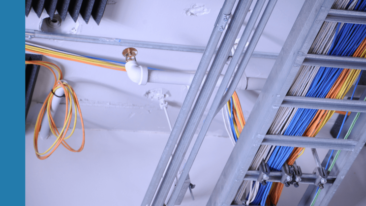 Many colourful cables are laid on the white ceiling.