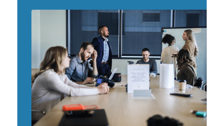 Sieben Personen stehen und sitzen in einem Meetingraum und beraten sich zu Themen der IT-Sicherheit.