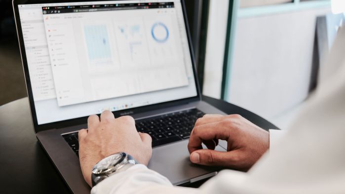 Mann mit großer Uhr am Handgelenk analysiert am aufgeklappten Laptop eine Auswertung