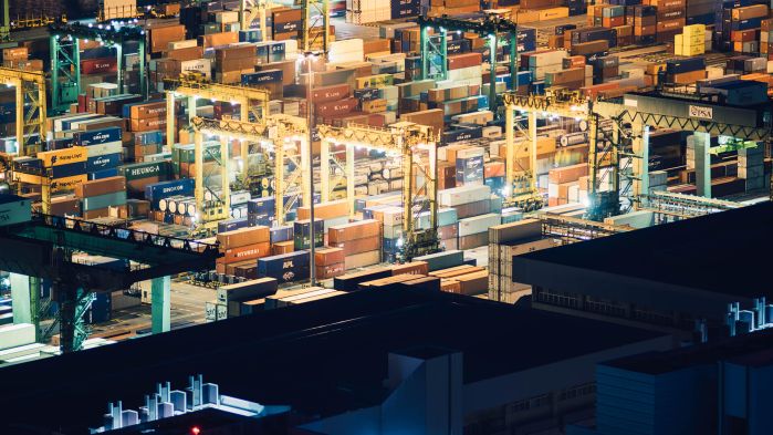 Many colorful cargo containers at port by night