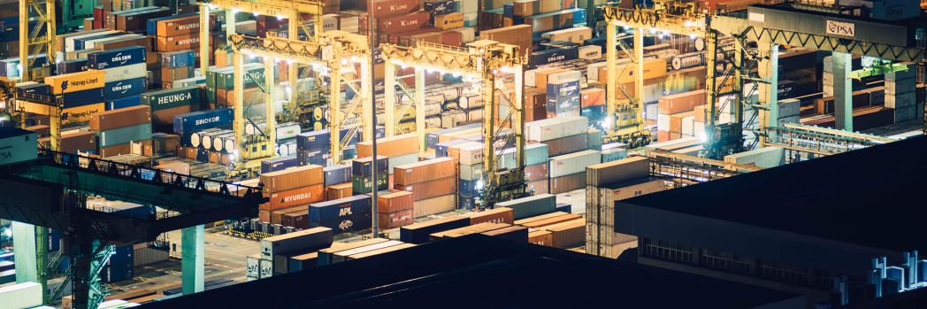 Many colorful cargo containers at port by night