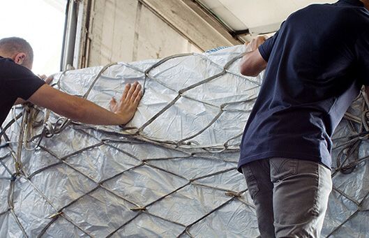 Zwei Logistikmitarbeiter sichern Stückgutsendungen auf einer Ladefläche – Symbol für effiziente und digitale Stückgutlogistik in modernen Logistiknetzwerken.