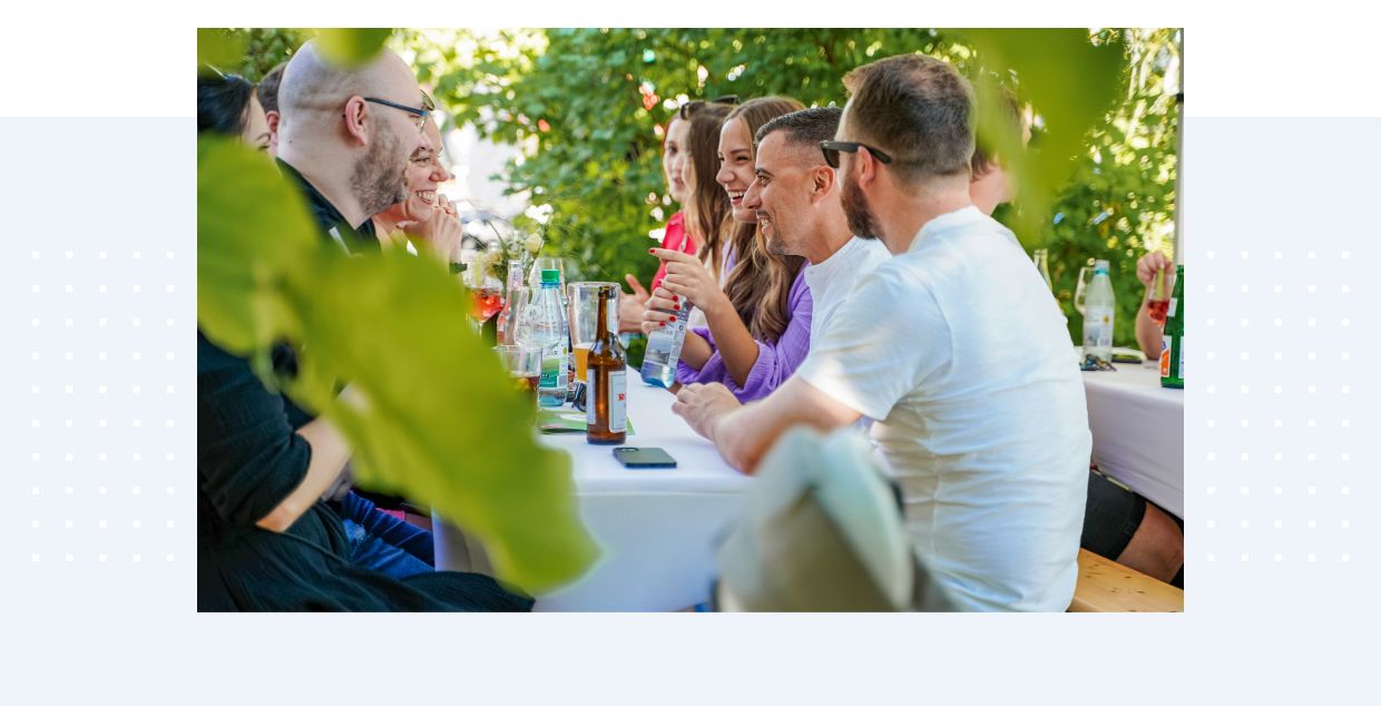 EIKONA Logistics Mitarbeiter sitzen an einem Tisch im Grünen und feiern.