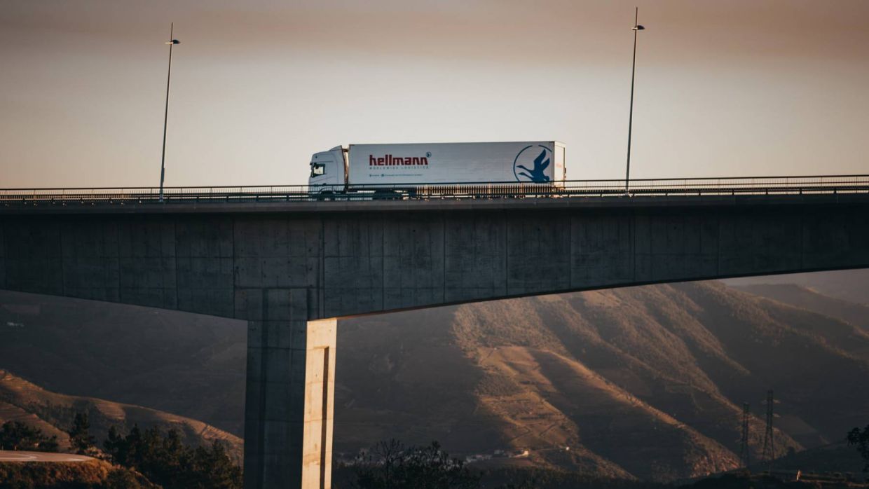 Ein LKW der Firma Hellmann überquert eine große Brücke.