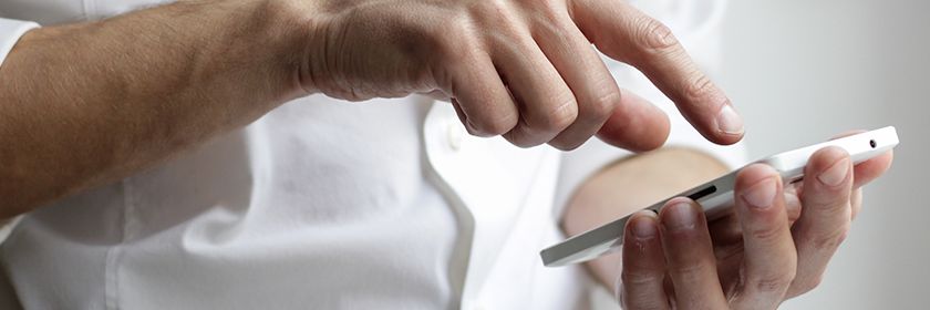 Man in white shirt typing on smartphone