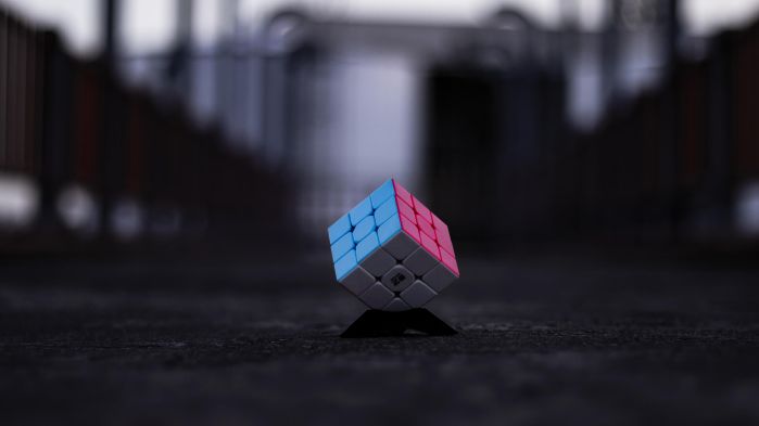 Zauberwürfel mit blauer, pinker und weißer Seite liegt auf einer dunklen Straße