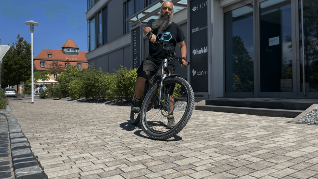 Ein Mann mit grauem schwarzem Bart steht mit seinem Jobrad vor dem Office Center in Volkach.