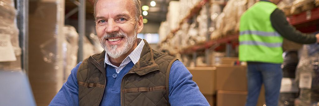 Ein Logistikmitarbeiter freut sich über die professionelle WLAN-Planung im Lager.