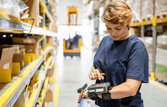 Warehouse employee uses Wi-Fi in a warehouse to operate mobile device.