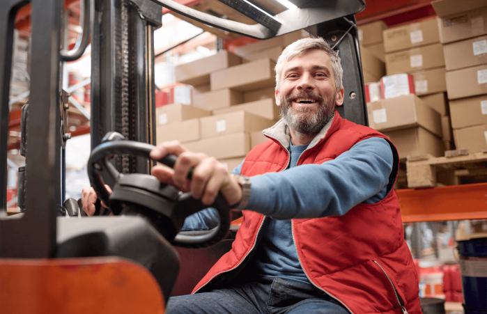 A forklift truck driver at work, while he is smiling.