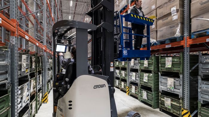 Employee in the warehouse records data on his mobile device in the forklift.