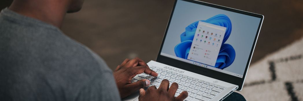 Mann sitzt an seinem Laptop und aktualisiert das Betriebssystem auf Windows 11