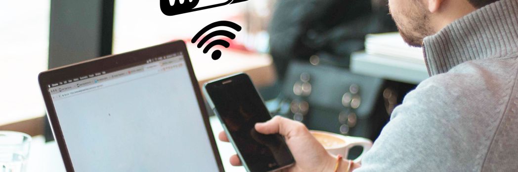 Auf dem Bild sind ein Laptop, ein Smartphone und der Schriftzug "Wifi 6" sichtbar.