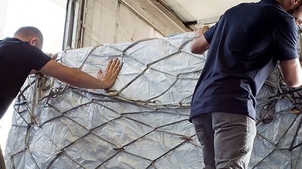 Zwei Logistikmitarbeiter sichern Stückgutsendungen auf einer Ladefläche – Symbol für effiziente und digitale Stückgutlogistik in modernen Logistiknetzwerken.