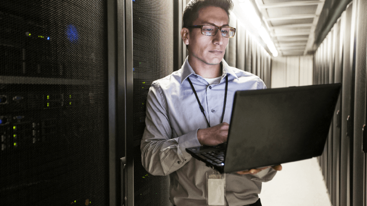Ein IT-Systemadministrator arbeitet in einer Serverfarm an einem Laptop