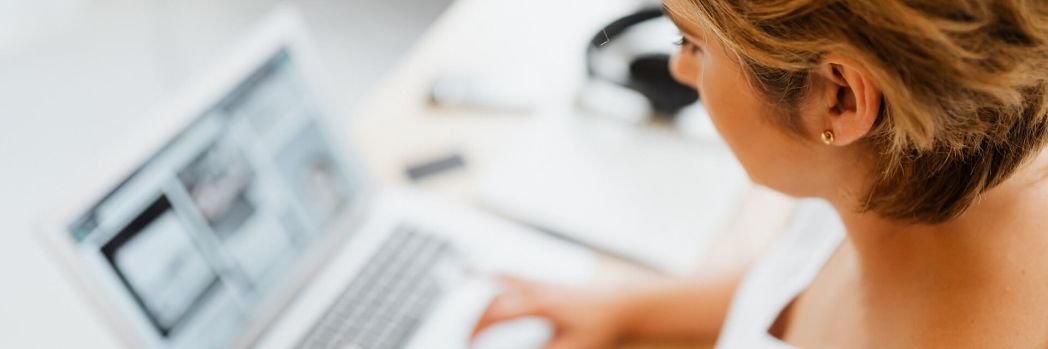 Blonde woman sitting at a desk and typing on a laptop