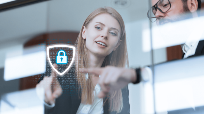 Blonde woman touches a lock icon on a glaswall in front of her with her finger.