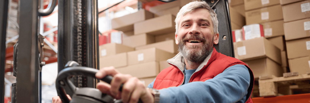 A forklift truck driver at work, while he is smiling.