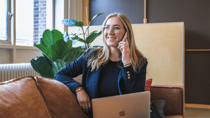 Woman sits on sofa with laptop on lap and makes phone call, which stands for the right to information for call notes