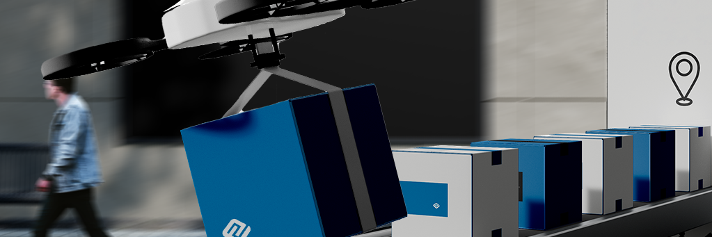 Es stehen mehrere blaue und graue Pakete in einer Reihe. Im Vordergrund fliegt eine Drohne mit einem blauen Paket weg.