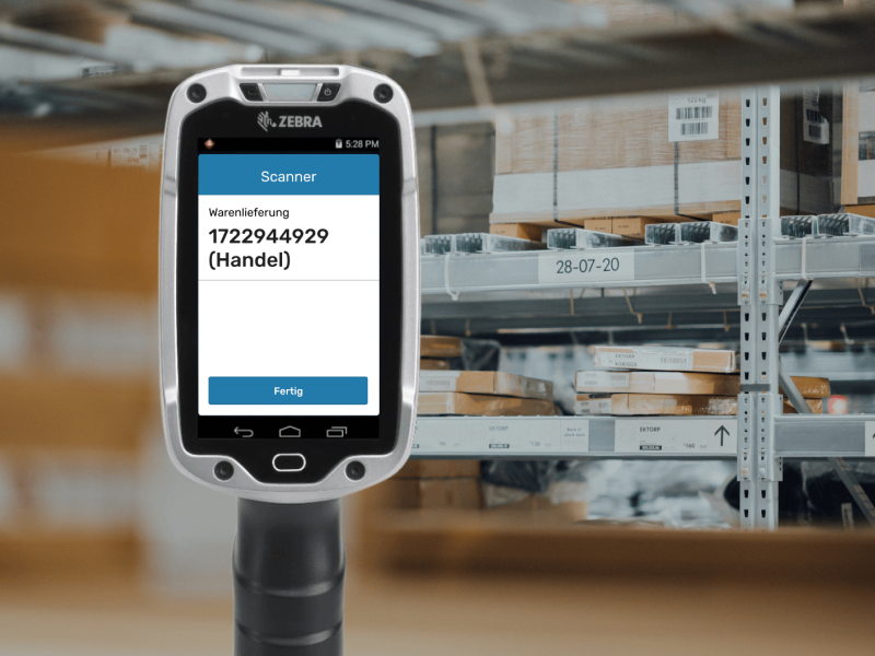 Im Hintergrund sind Lagerregale zu sehen. Im Vordergrund ist ein Scanner zu sehen.