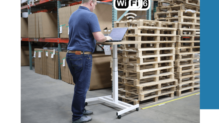 A person is working on a laptop in a warehouse and is connected to WiFi 6.