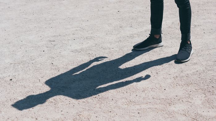 Man standing in the sun looking at his shadow, which stands for data protection of sensitive data.
