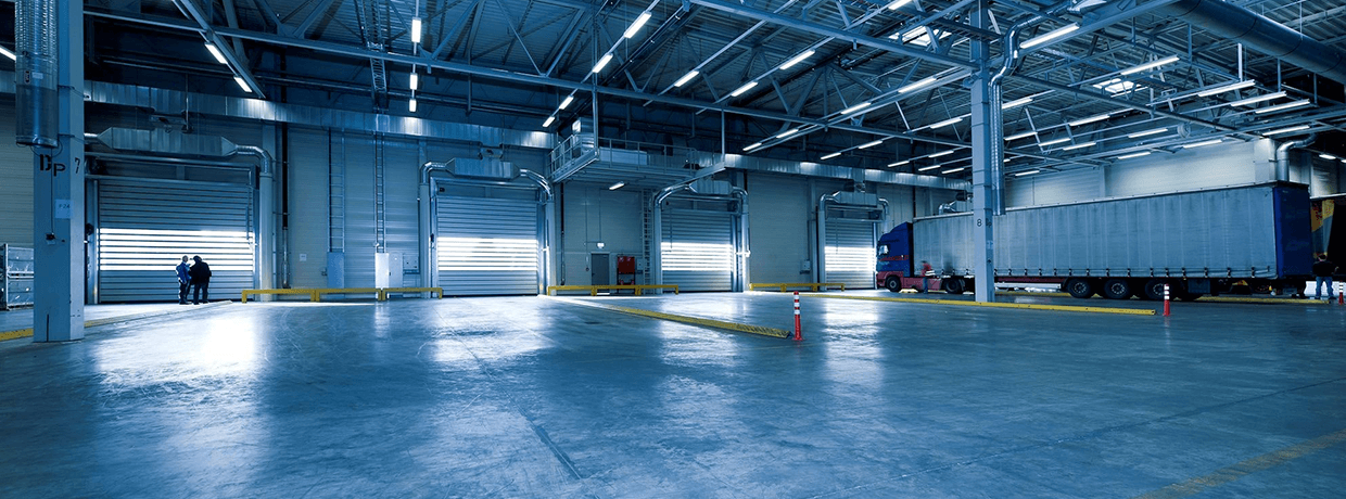 Eine große Logistikhalle, in der man Tore, LKWs und Personen sehen kann.