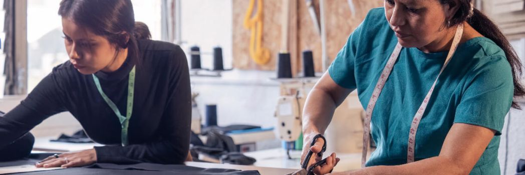 Mother and daughter sewing a dress at a sewing table.