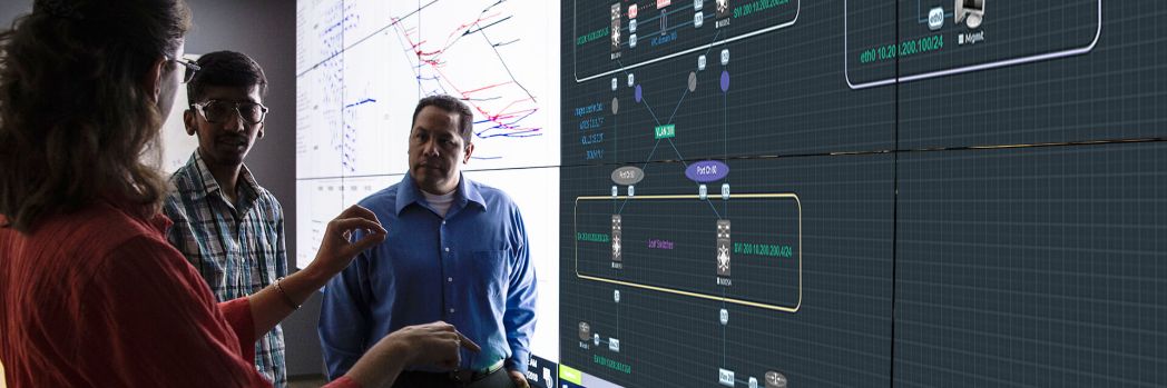 Team stands in front of a whiteboard on which an EVE-NG environment is mirrored