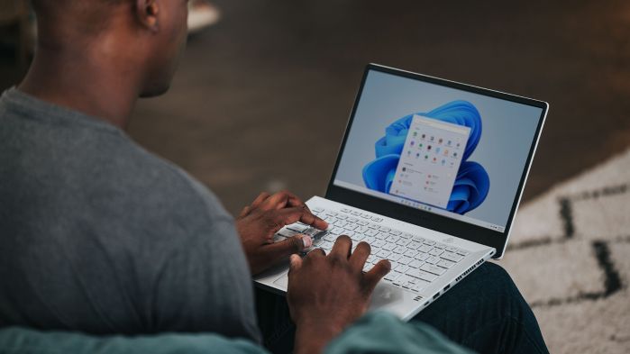 Mann sitzt an seinem Laptop und aktualisiert das Betriebssystem auf Windows 11