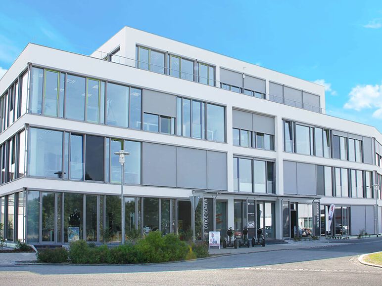 Weißes Bürogebäude mit großer Fensterfront.