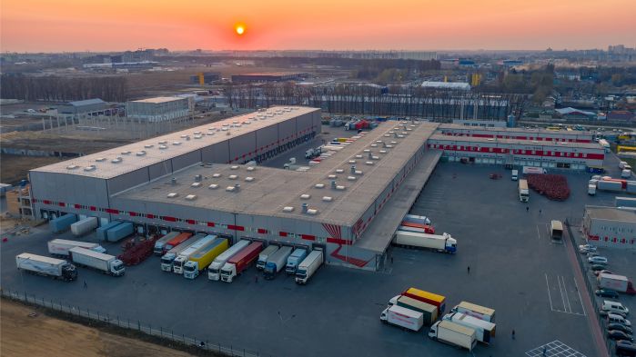 In the yard of a forwarding agency, trucks are being loaded.