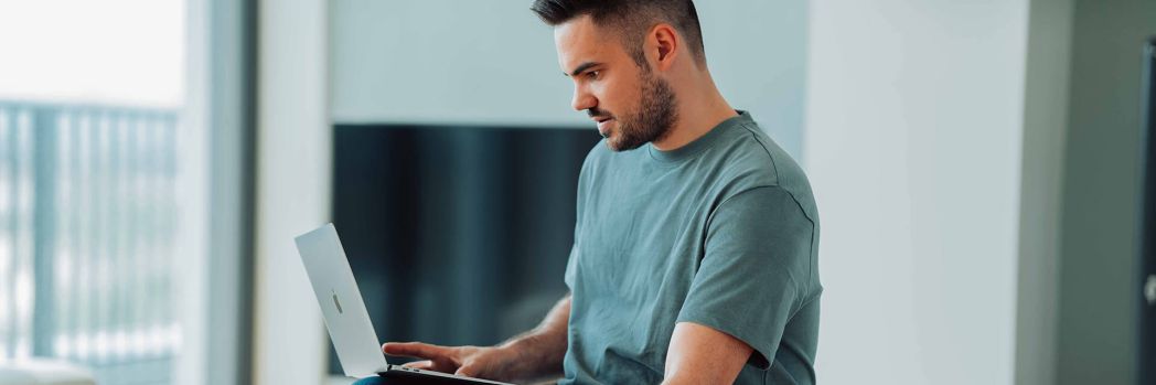 Employee sits with his laptop on the couch in the home office and mitigates cyber dangers because he is prepared through knowledge and diligence