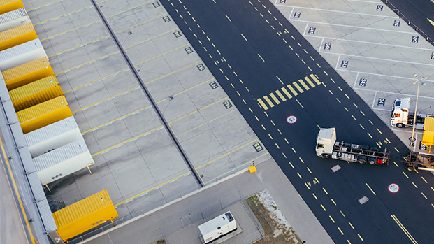 Logistics site with halls and yellow and white lorries.