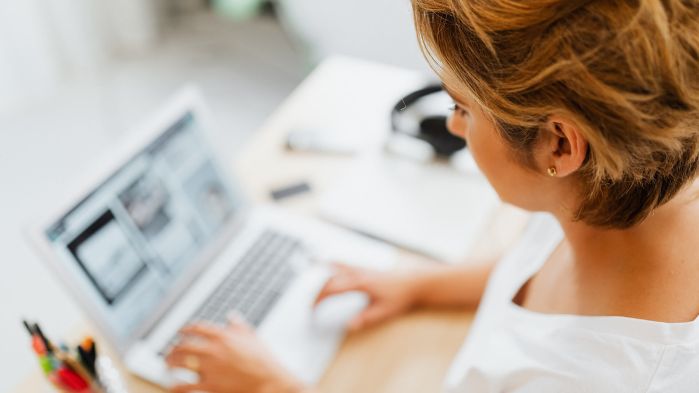 Blonde Frau sitzt an einem Schreibtisch und tippt auf einem Laptop