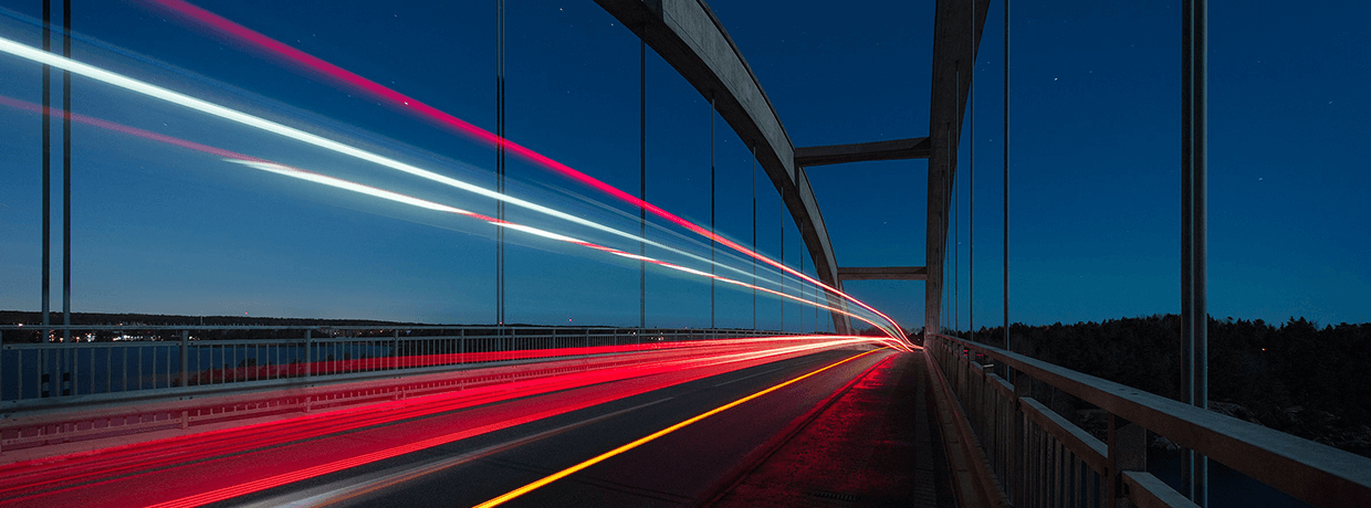 Beliefern Sie Privatkunden schnell und effizient mit unseren Lösungen Streifen sind aufgrund eines Bewegungsunschärfe-Effektes über einer Brücke zu sehen.