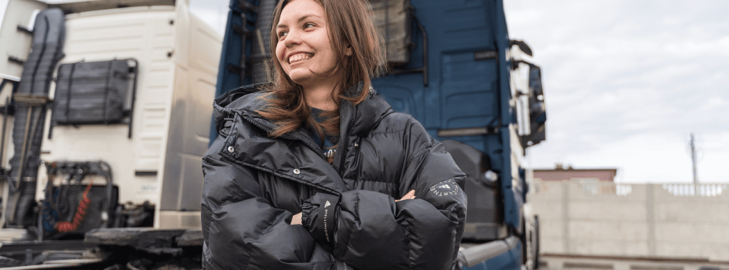 Eine Person vor zwei LKWs schaut zufrieden nach links.
