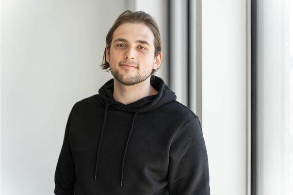 Ein Auszubildender in einem Büro, der einen schwarzen Pullover trägt.