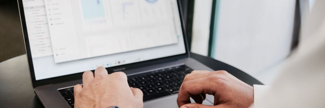 Mann mit großer Uhr am Handgelenk analysiert am aufgeklappten Laptop eine Auswertung
