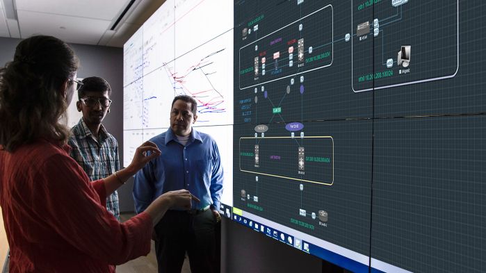 Team stands in front of a whiteboard on which an EVE-NG environment is mirrored