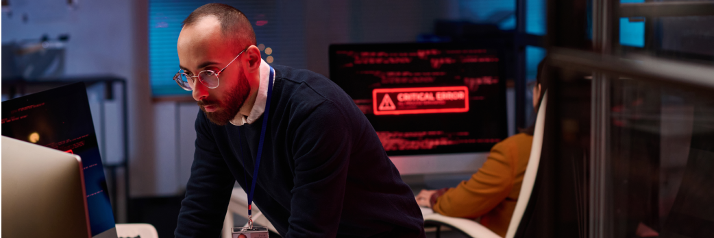 A man looks concentrated at a screen during an IT emergency.
