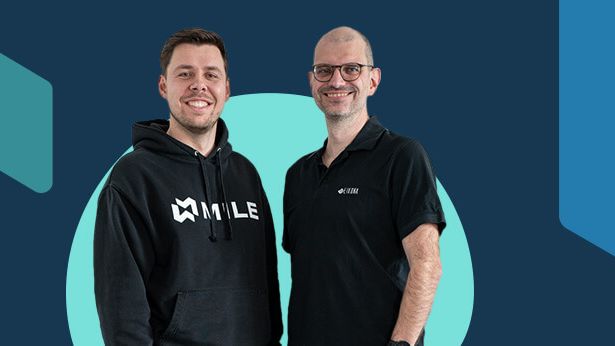 Ein blauer Hintergrund, auf dem Steffen Hauptmann und Stefan Seufert im Vordergrund abgebildet sind.