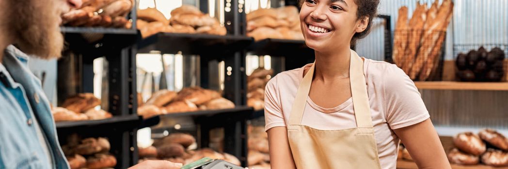 Mann zahlt in Bäckerei mit EC-Karte, welche für Zahlungsaufschub und lange Zahlungsziele in der Logistik stehen